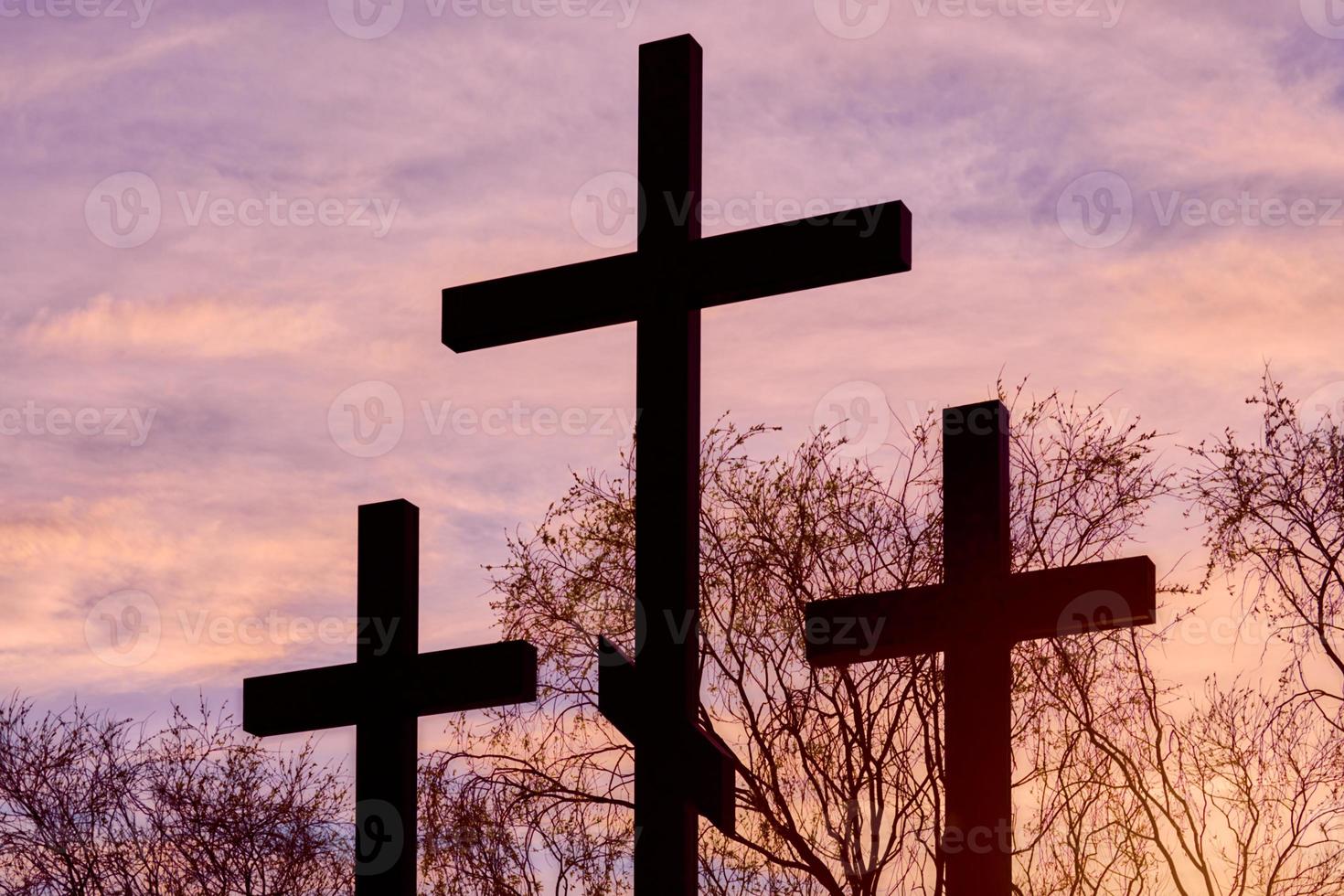 Three crosses in silhouette at sunset, dramatic sky photo