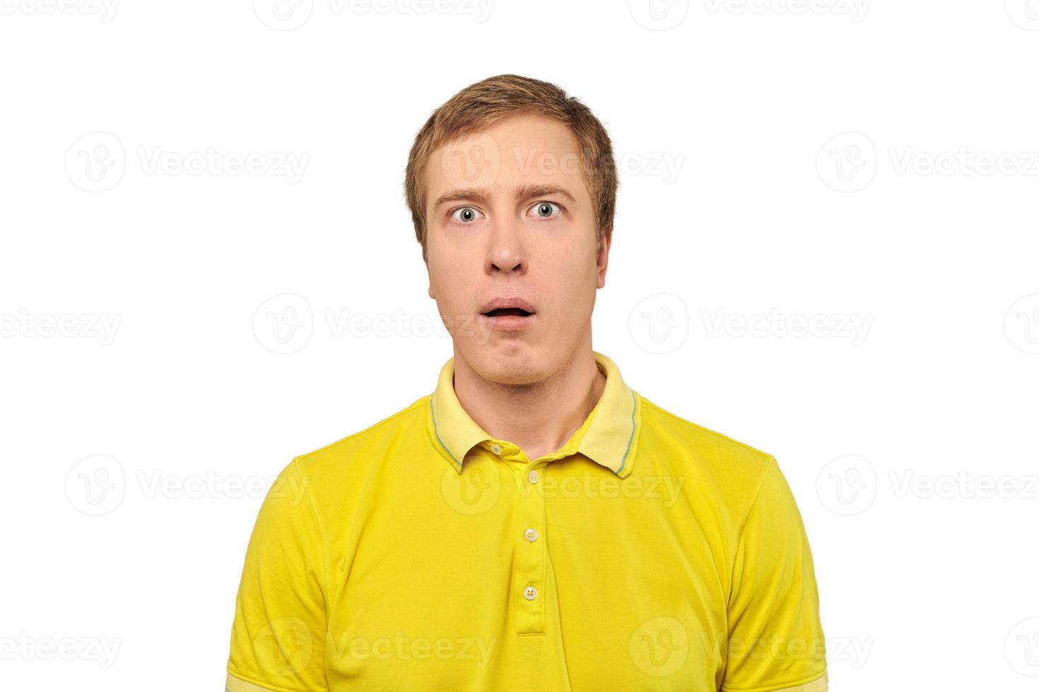 Surprised young man with funny facial expression in yellow T-shirt, white isolated background photo