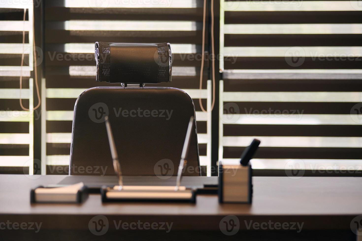 lugar de trabajo de la oficina de negocios. lugar de trabajo para jefe, jefe u otros empleados. mesa y silla cómoda. luz a través de las persianas entreabiertas foto