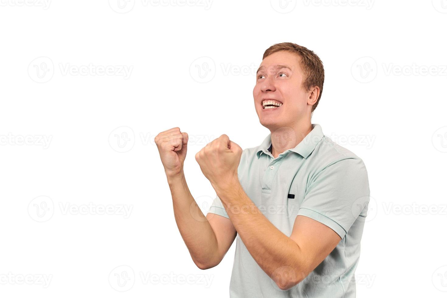 Successful smiling guy in mint T-shirt rejoices success, white background, triumph achievement photo