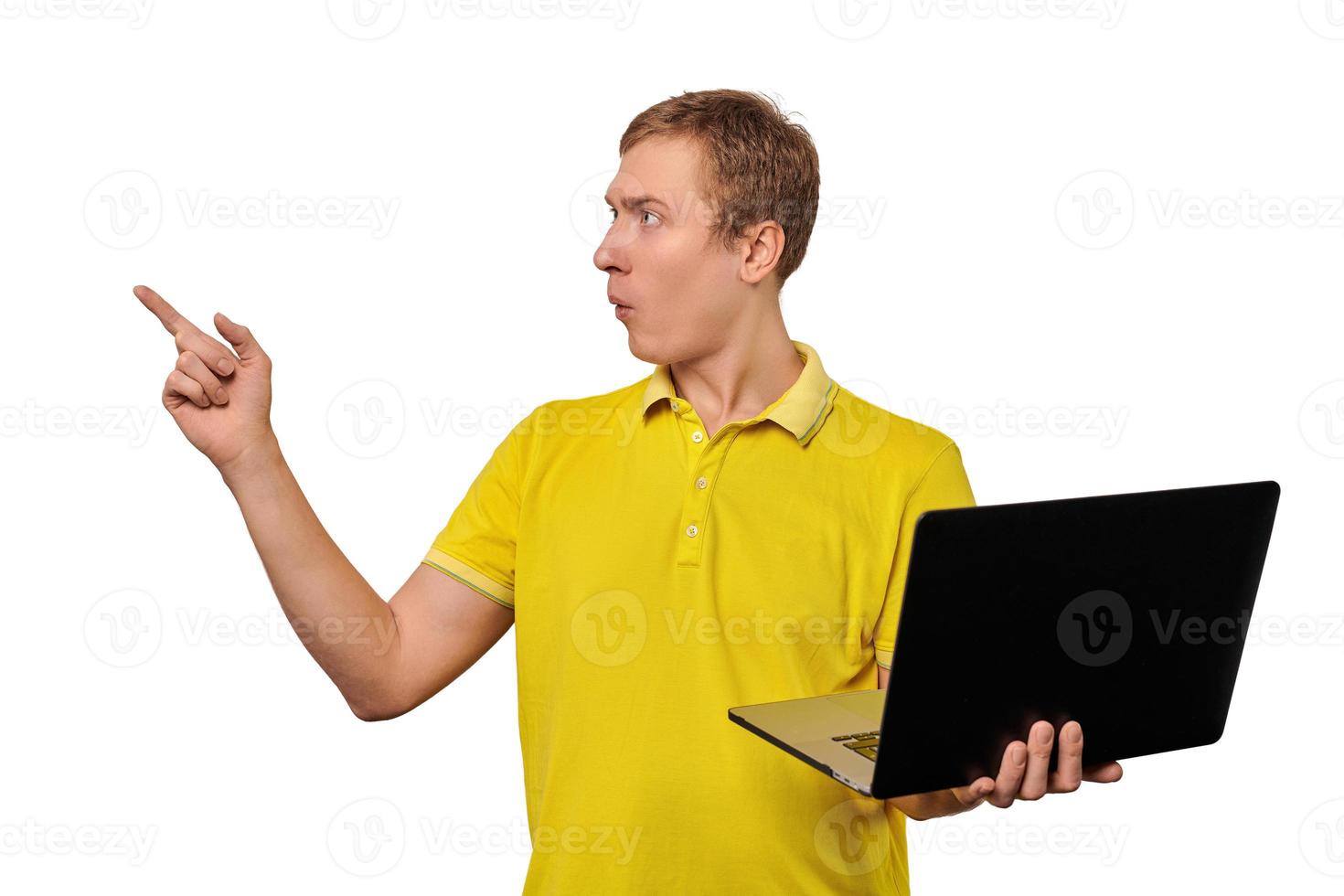 Puzzled young man with laptop pointing with finger isolated on white background, male confused face photo