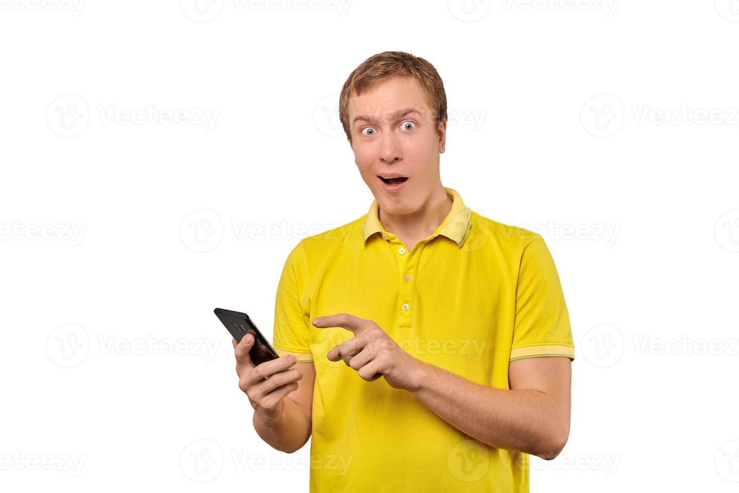 Surprised young man with smartphone, funny guy holding phone isolated on white background photo