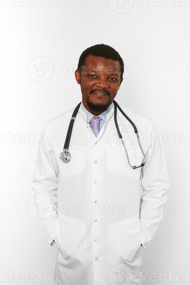 Smiling black bearded doctor man in white coat with stethoscope isolated on white background photo