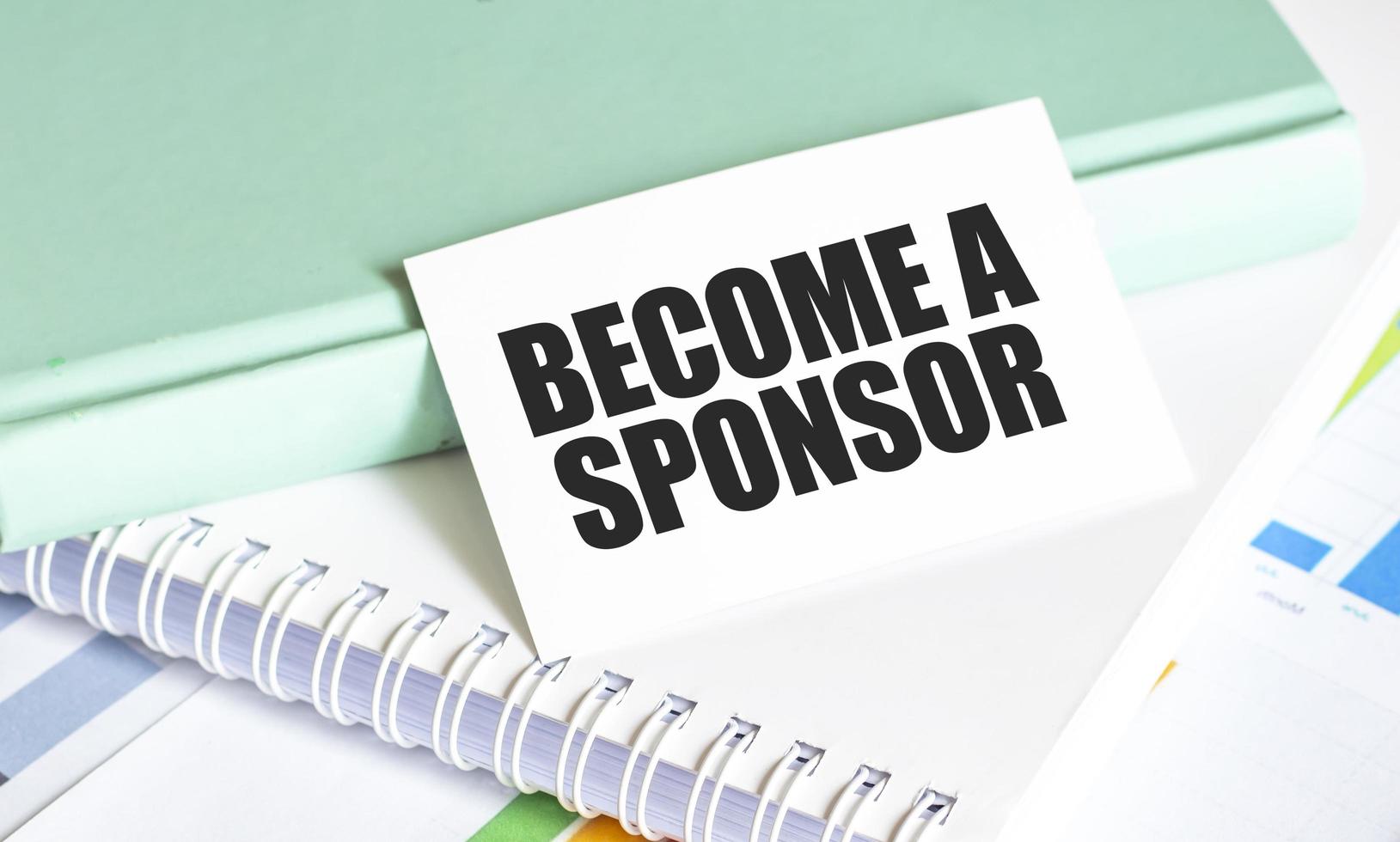 card with text BECOME A SPONSOR on charts and notepads photo