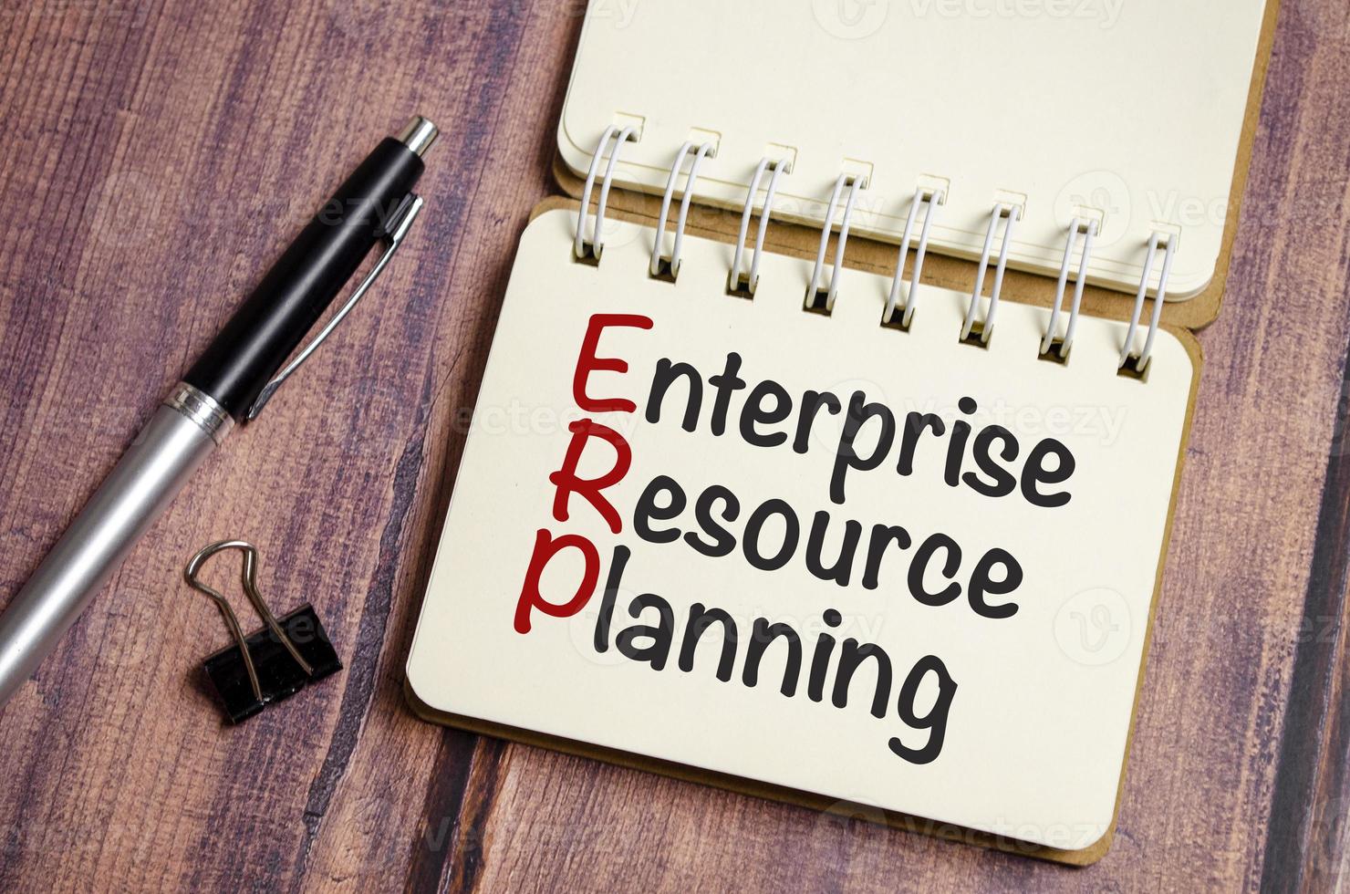 erp - enterprise resource planning words on notebook and pen photo