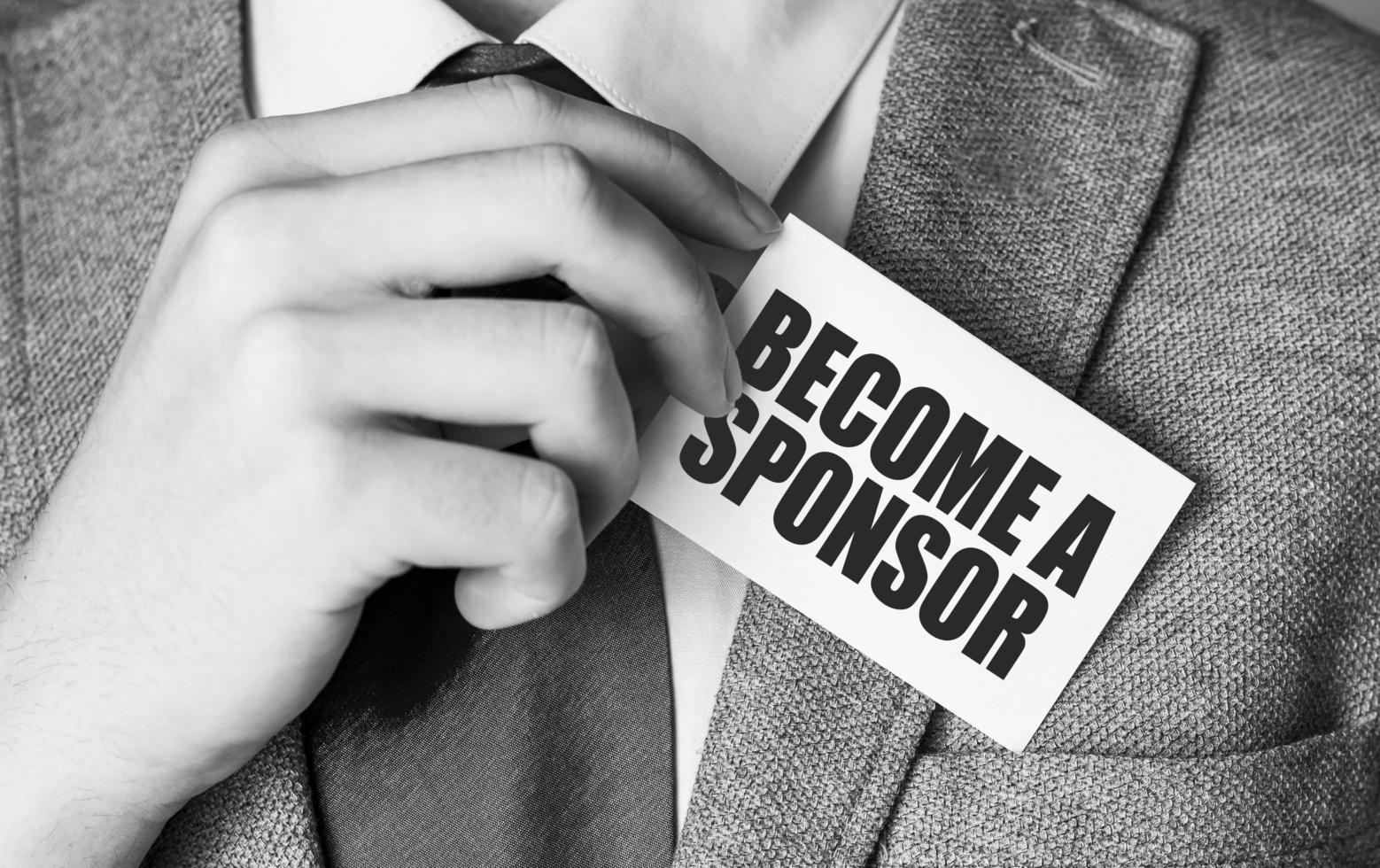 BECOME A SPONSOR on white business card and hands photo