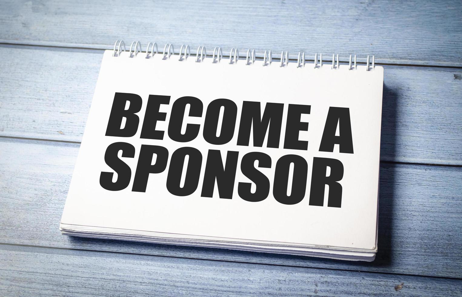 BECOME A SPONSOR text on blue wooden background photo