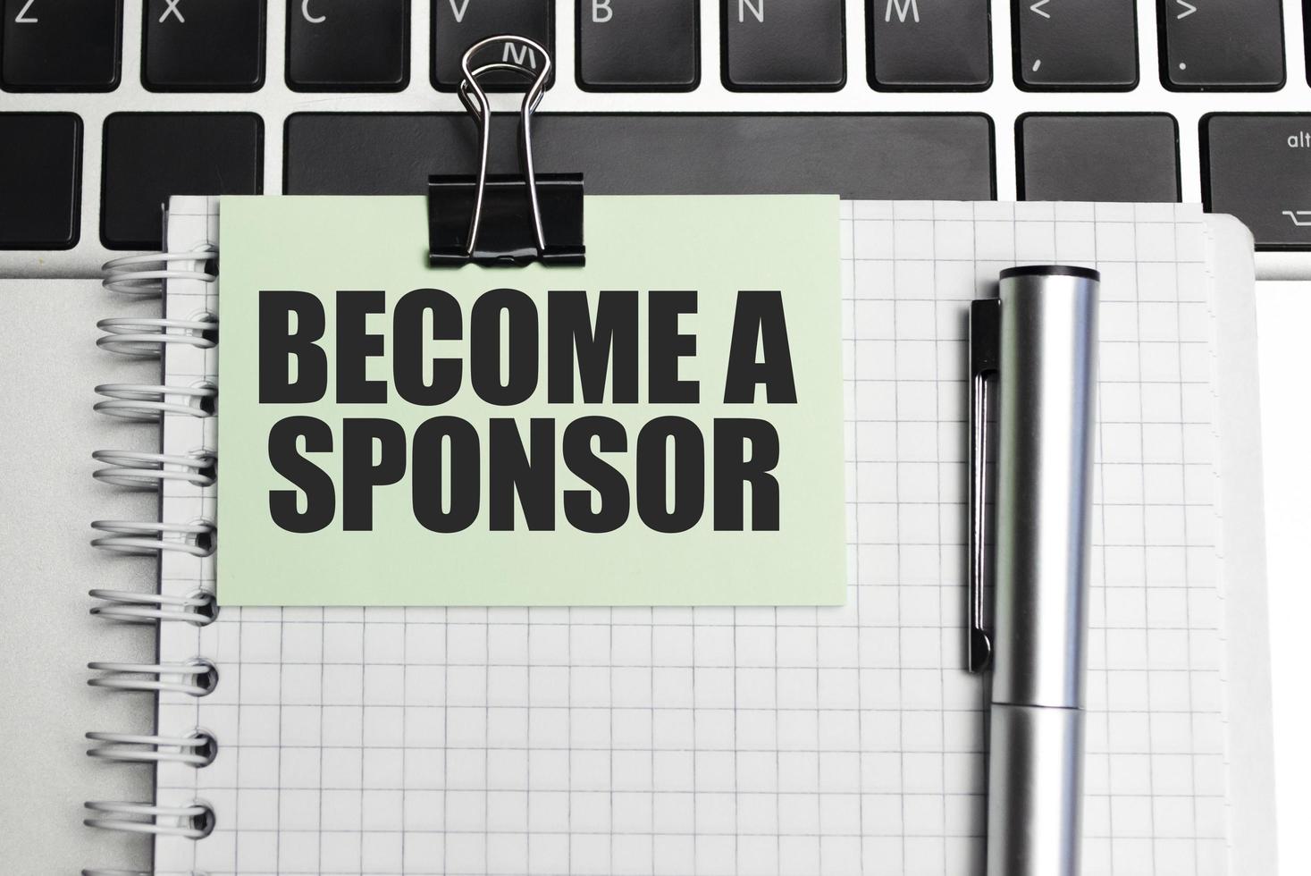 BECOME A SPONSOR text and notepad with pen, charts and calculator photo