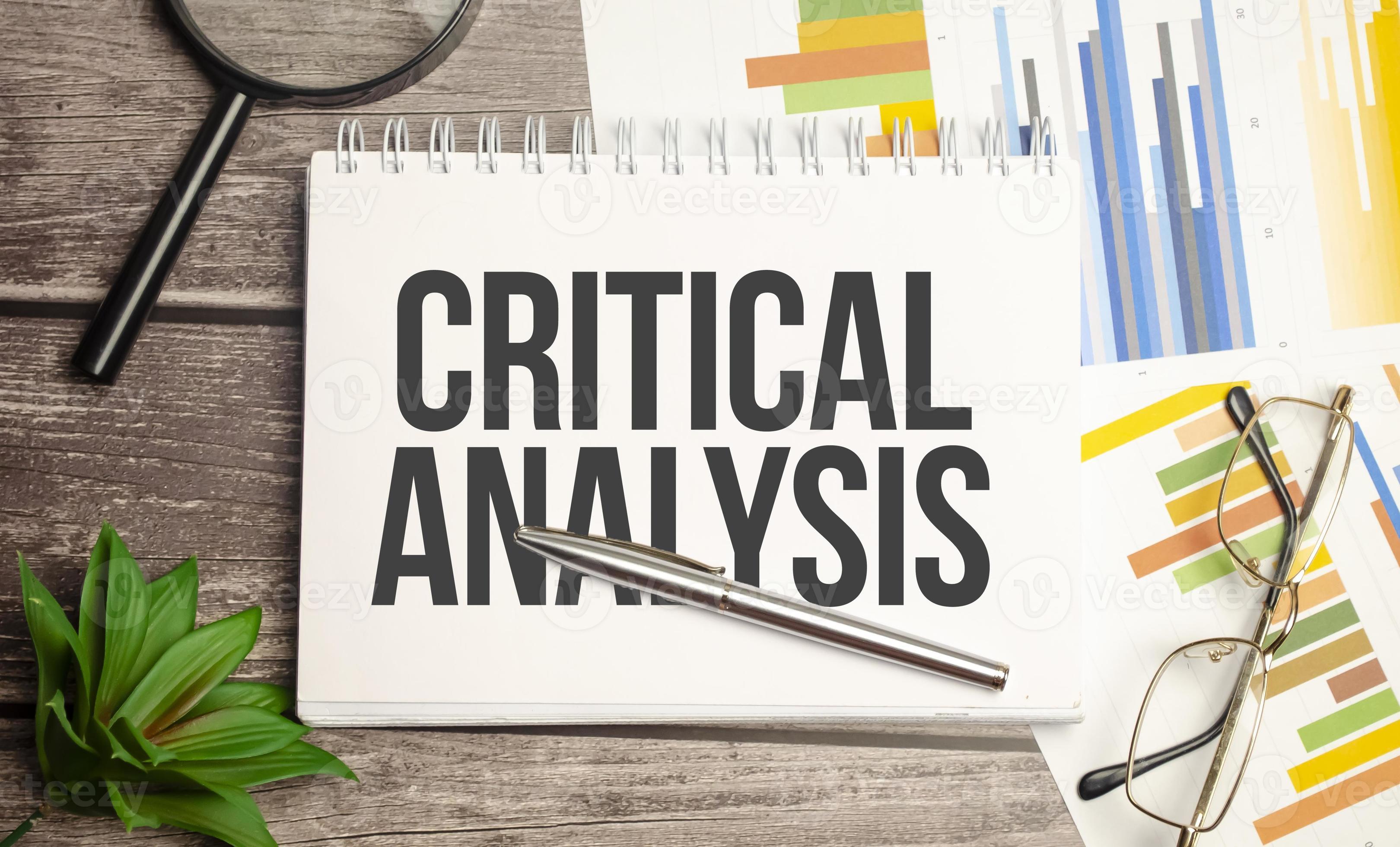 CRITICAL ANALYSIS words on notepad with magnifying glass and charts ...