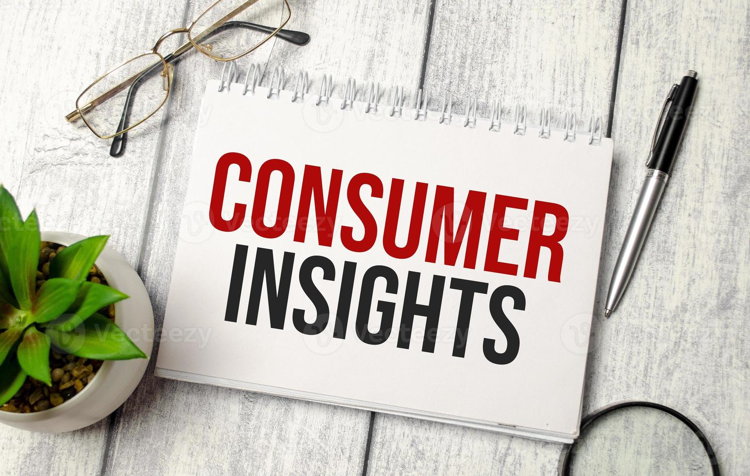 The text Consumer insights on paper notepad and calculator photo
