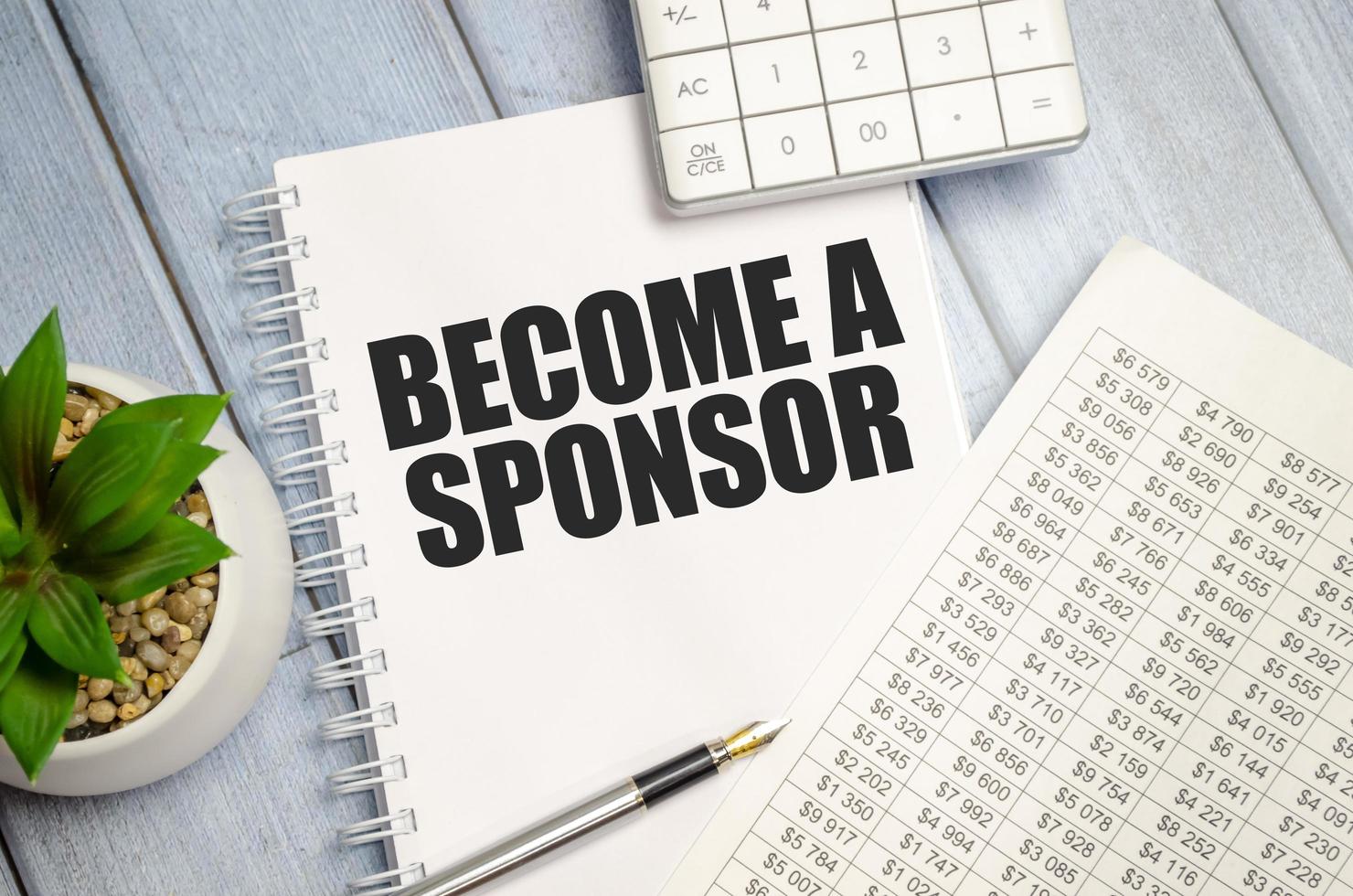 BECOME A SPONSOR word on notepad with glasses and chart photo