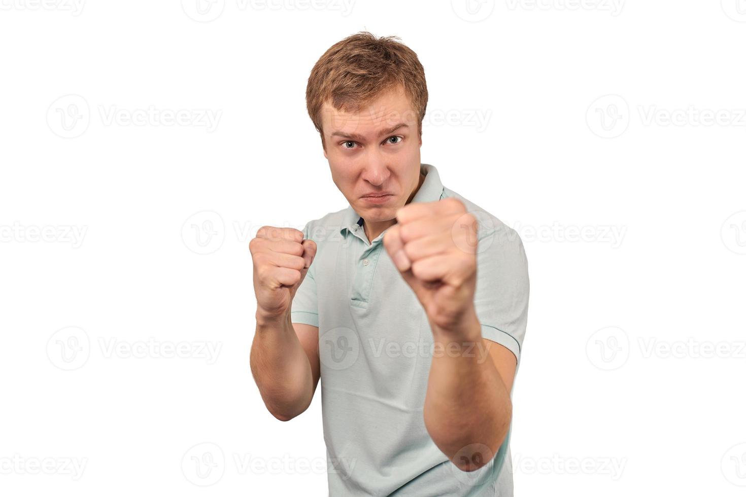 Angry young man in mint T-shirt ready to fight with fists isolated on white background photo