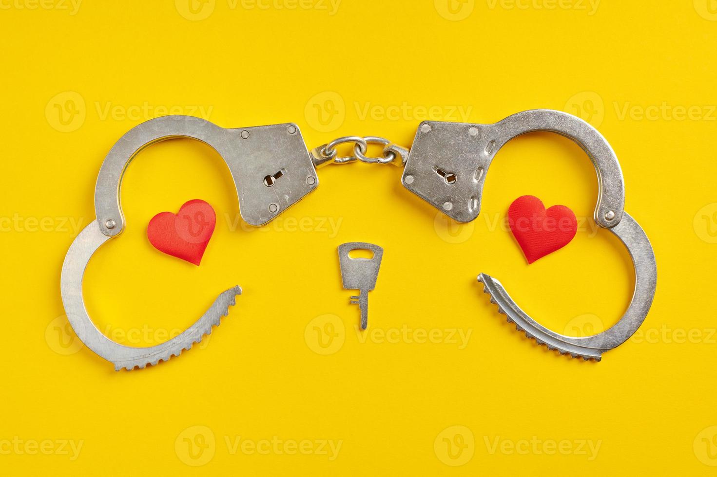 Handcuffs smile shape on yellow background. Freedom concept. photo