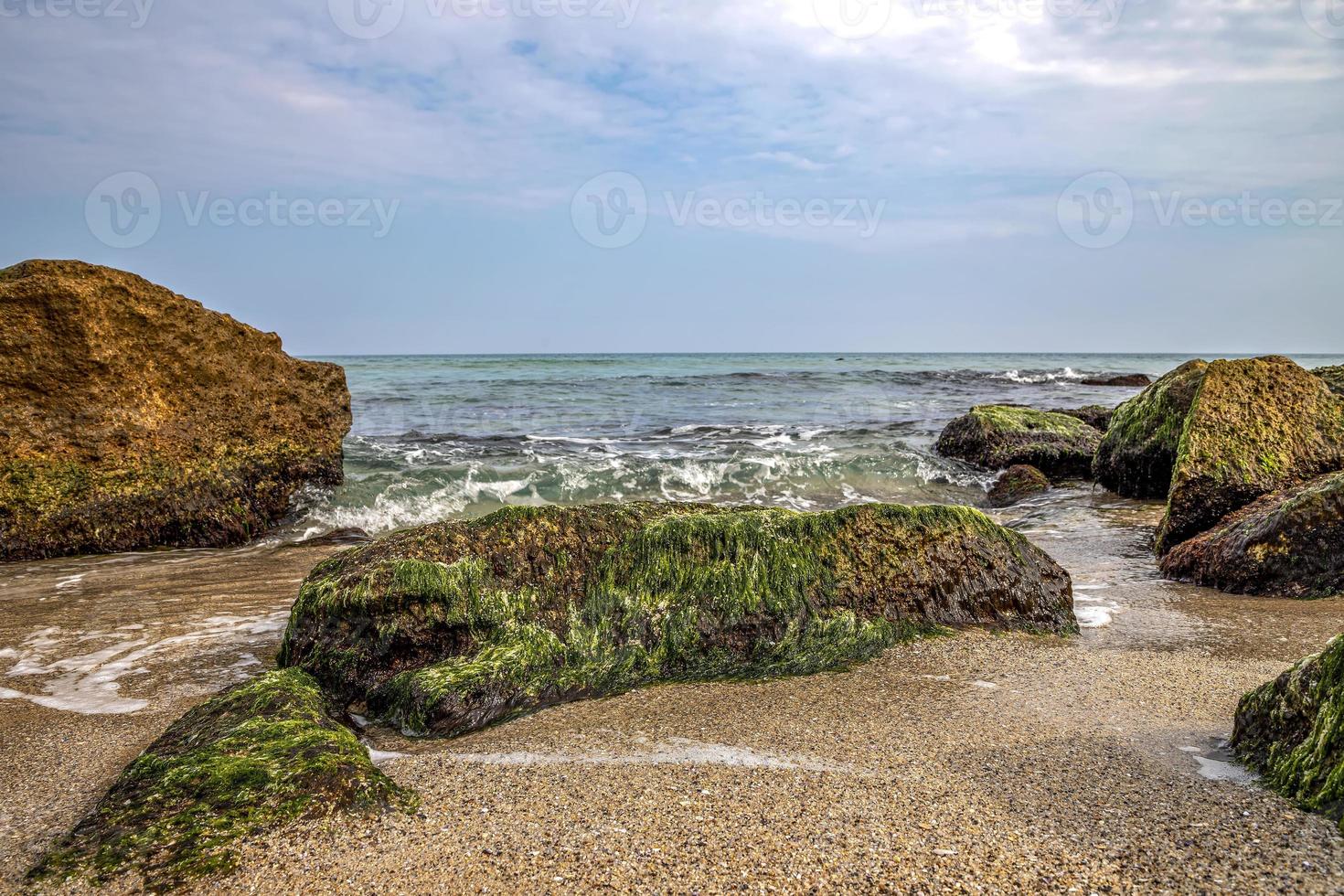 Dey view of a beautiful seascape with a close view of stone with moss. Blurred background. photo