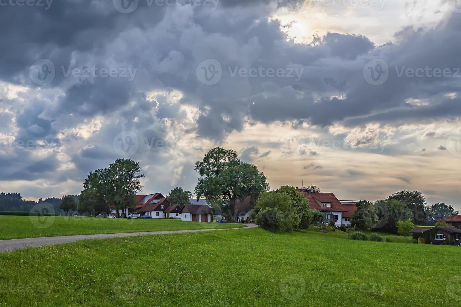 idyllic landscape with greenfield, road, and traditional german farmhouses. photo