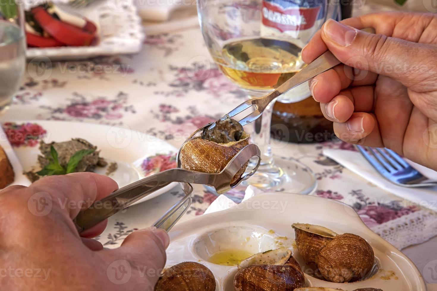 a woman eating delicious escargots with lemon on the table photo