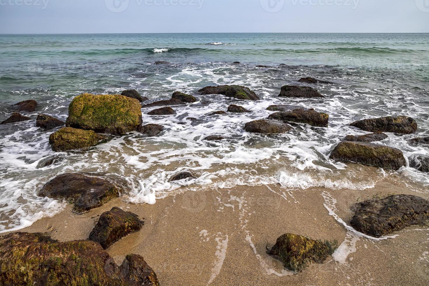 día de la belleza vista de la orilla del mar con rocas en el agua foto