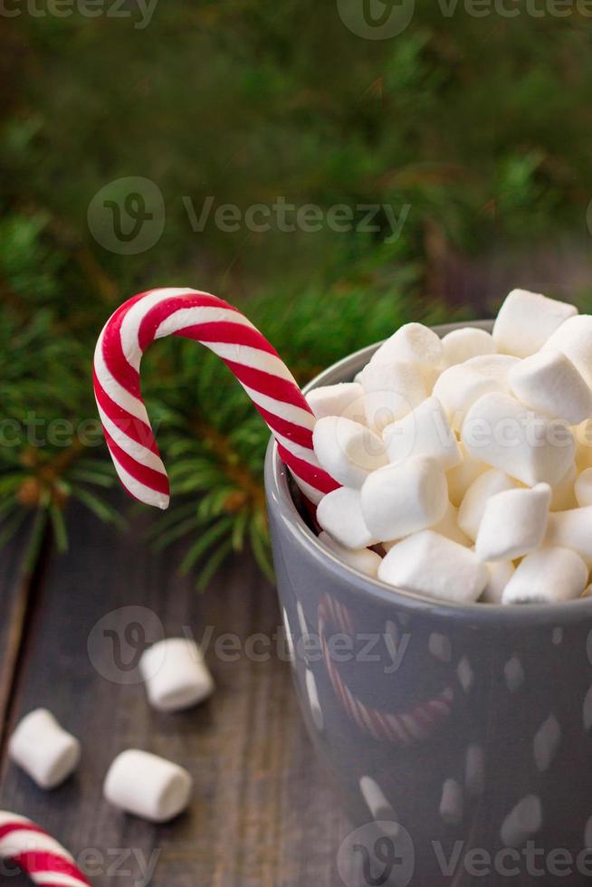 Hot coffee chocolate with marshmallow on rustic wooden table background, candy canes gift boxes fir tree photo