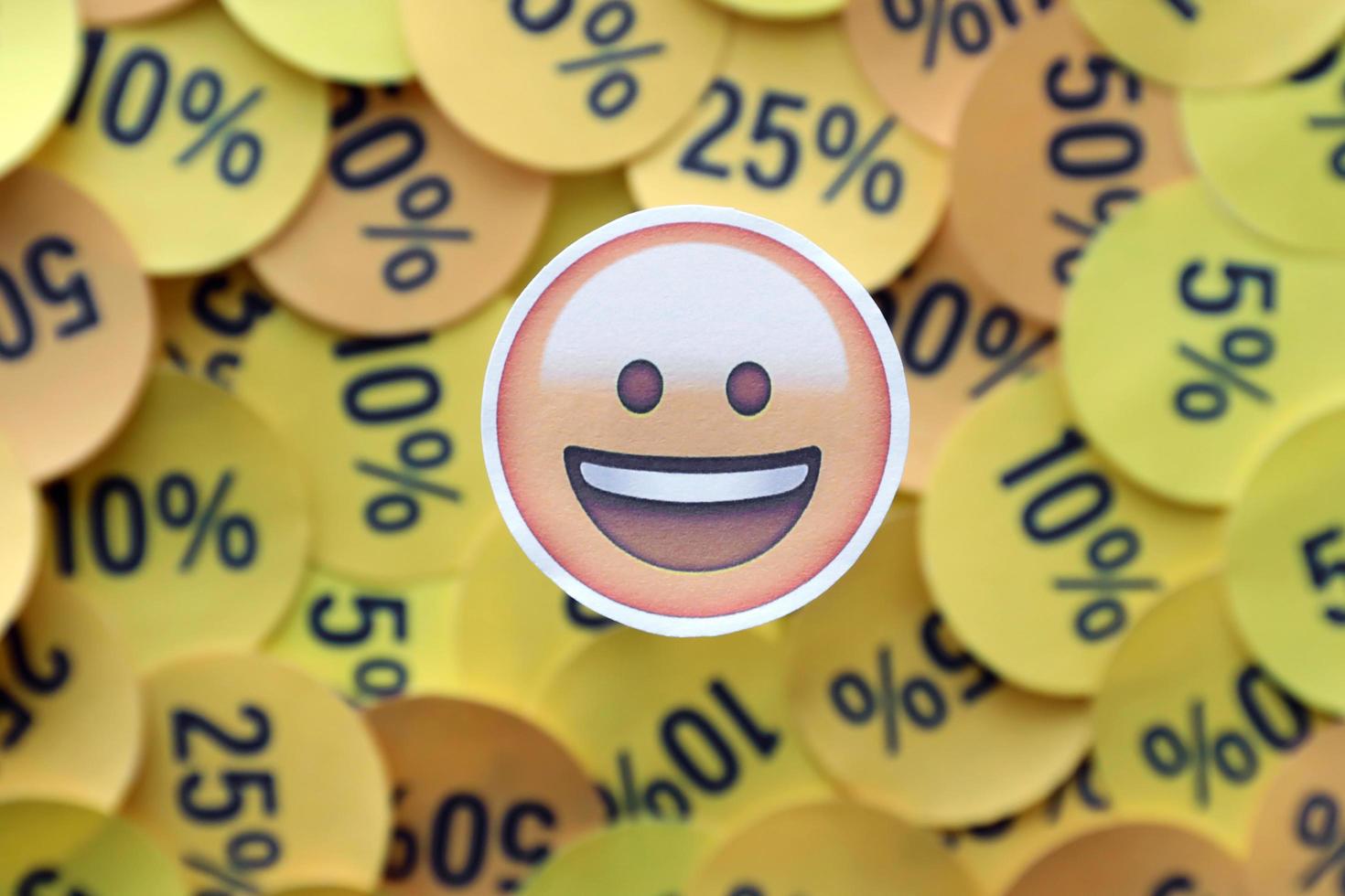 Ternopil, Ukraine - May 8, 2022 Happy emoji sticker on large amount of yellow stickers with percentage values for black friday or cyber monday photo