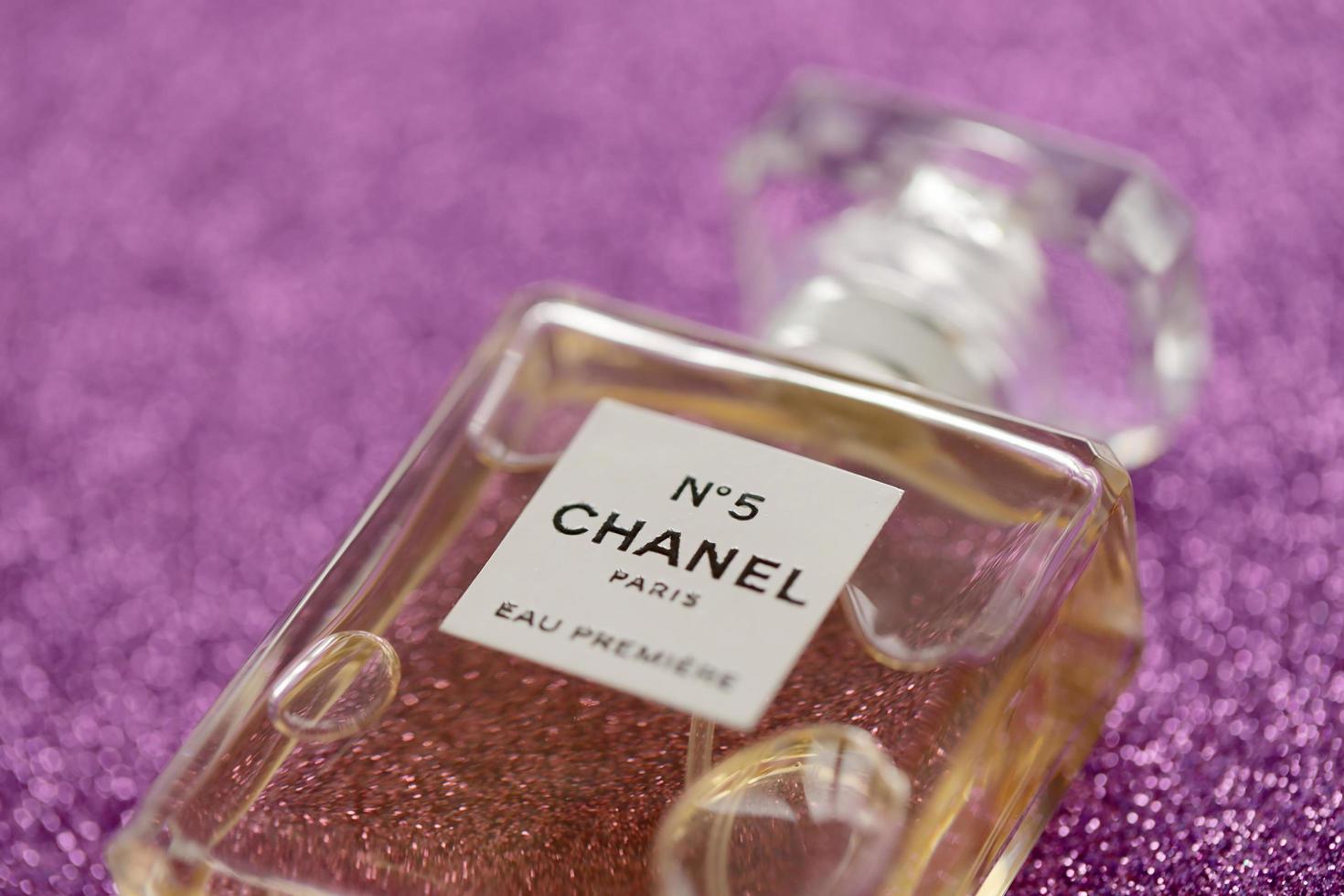TERNOPIL, UKRAINE - SEPTEMBER 2, 2022 Chanel Number 5 Eau Premiere worldwide famous french perfume bottle on shiny glitter background in purple colors photo
