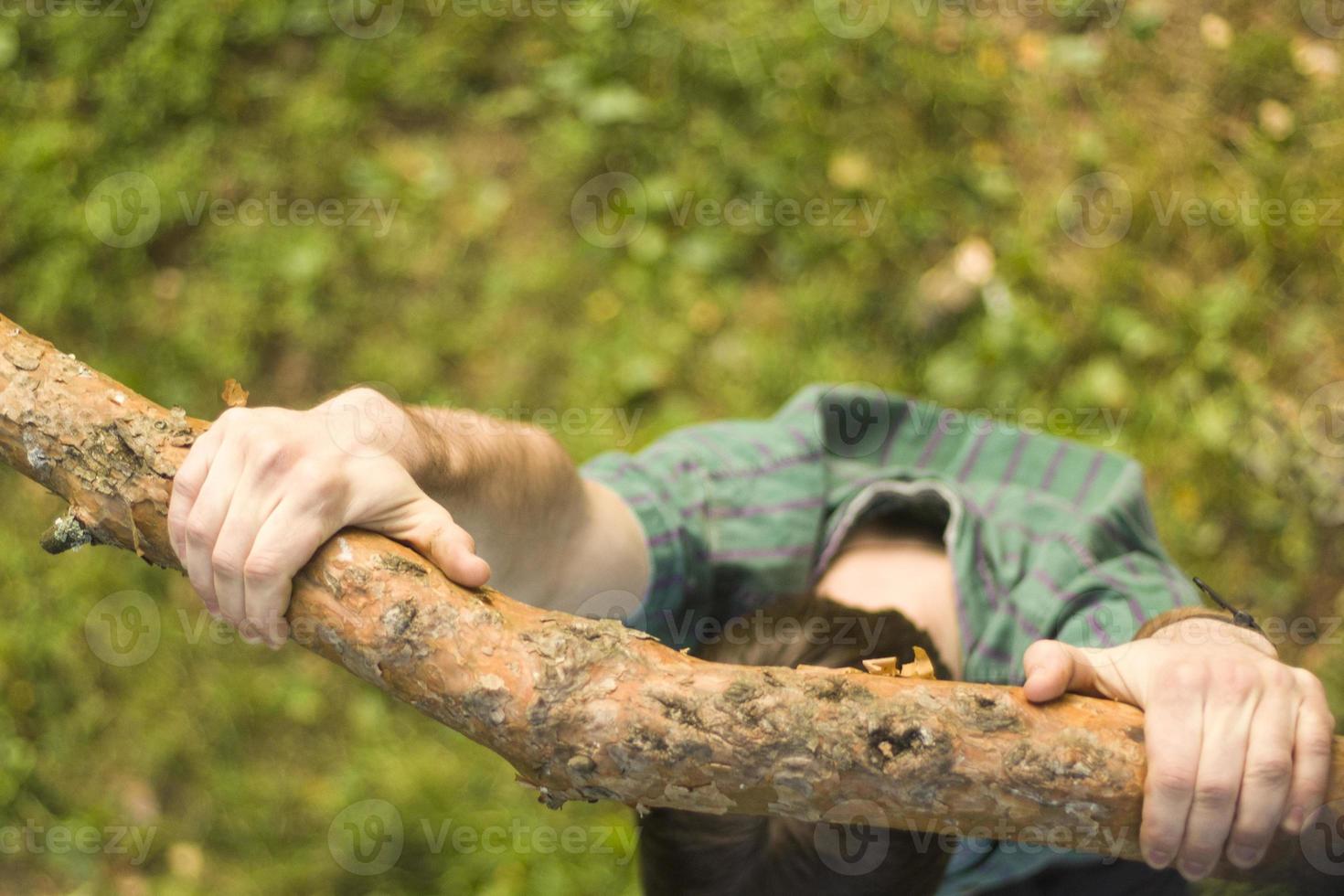 Hands hold on to branch. Guy is hanging on tree branch. Man on top. Strong grip with hands. photo
