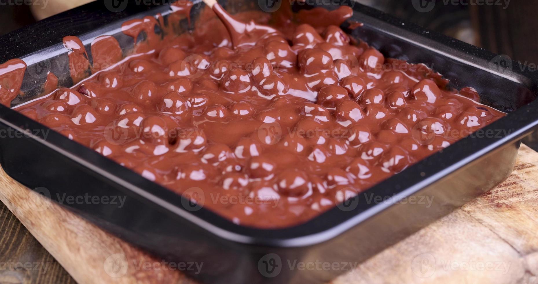 adding roasted hazelnuts to melted liquid chocolate photo