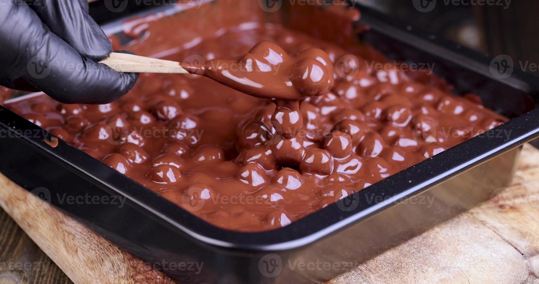 adding roasted hazelnuts to melted liquid chocolate photo
