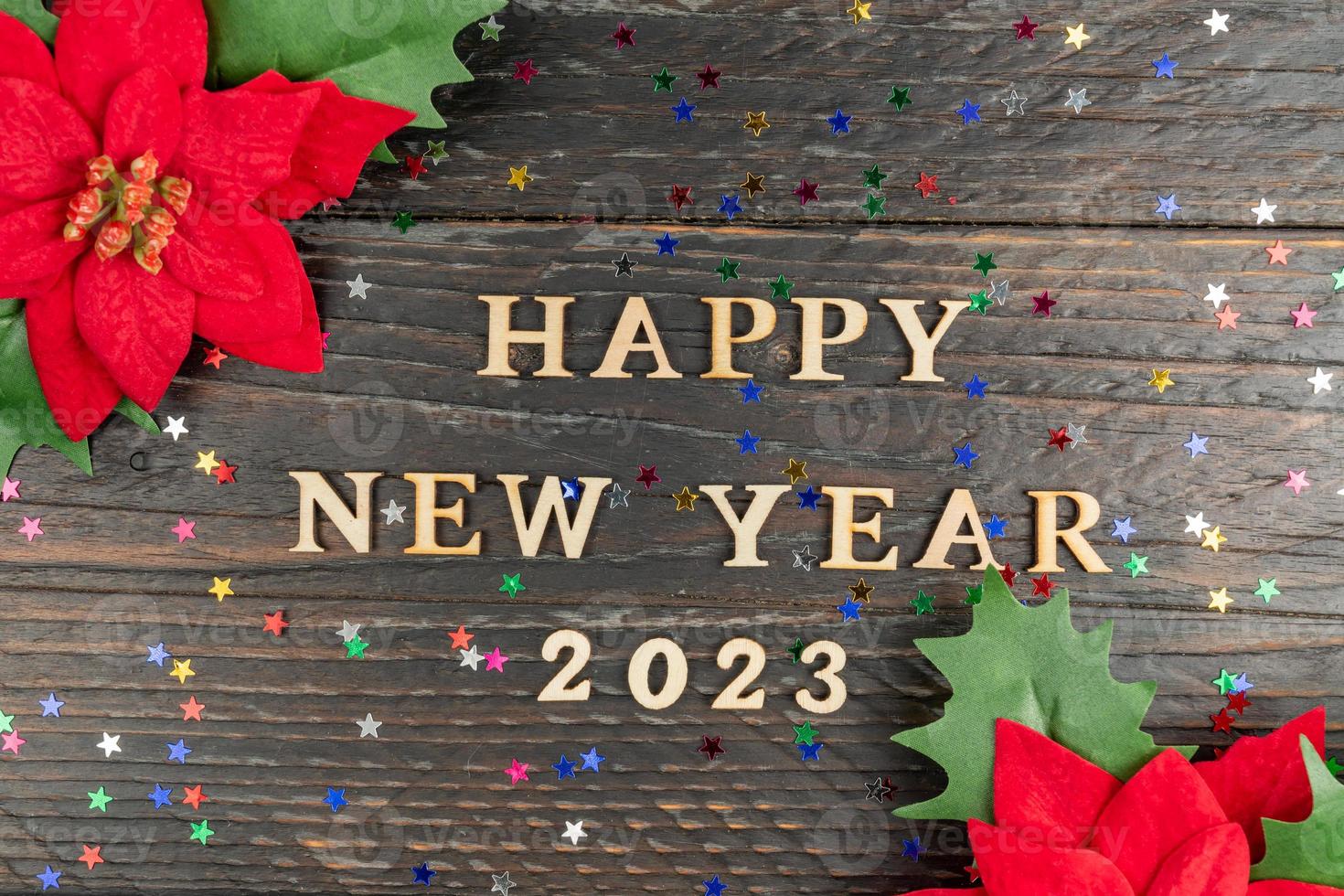 Happy New year 2023 celebration. Wooden text and poinsettia on wooden background. Flat lay. photo