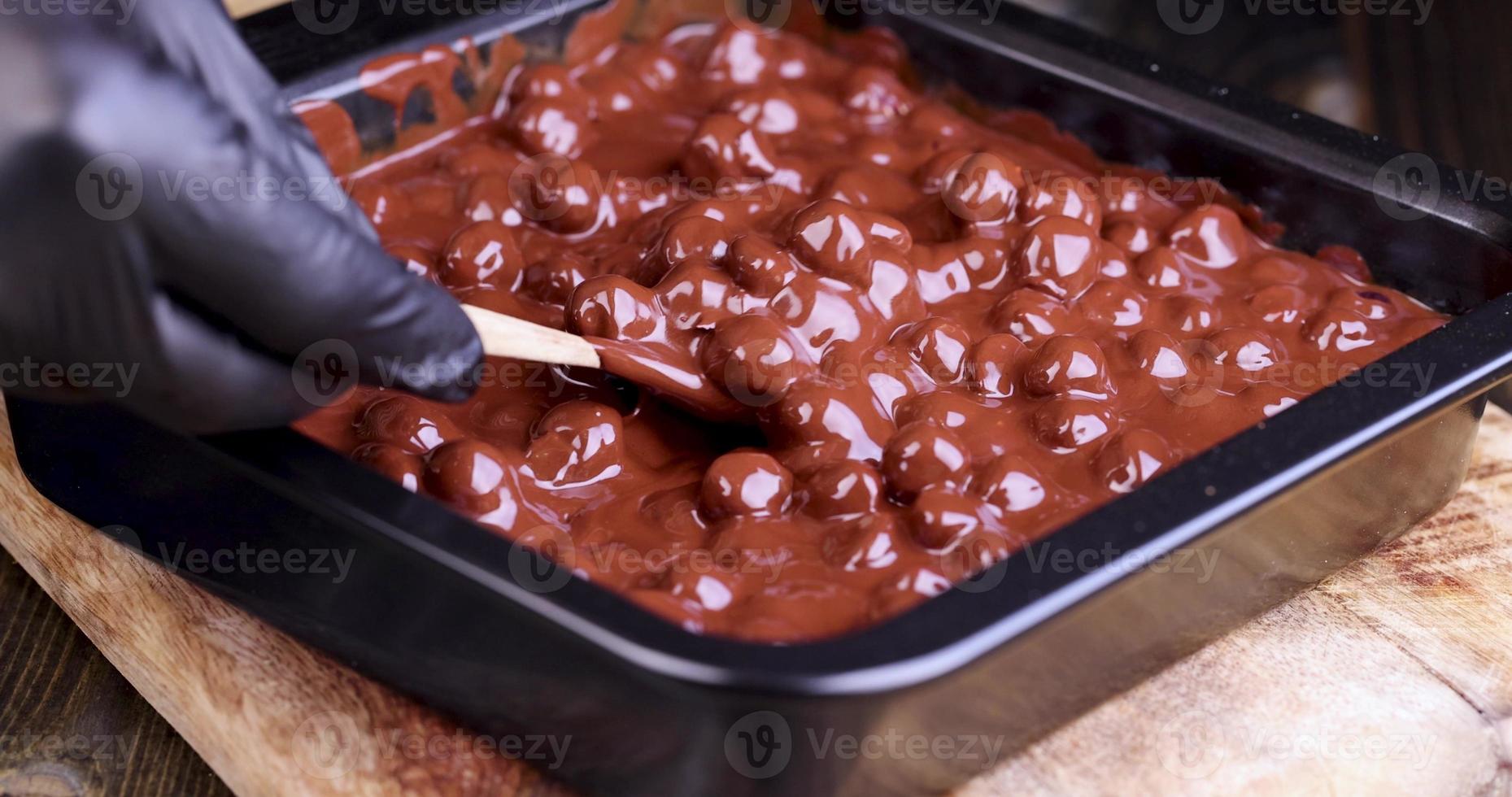 adding roasted hazelnuts to melted liquid chocolate photo
