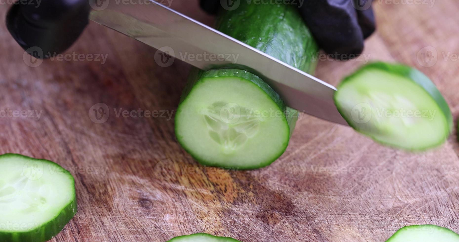 cut a ripe long green cucumber on a board photo