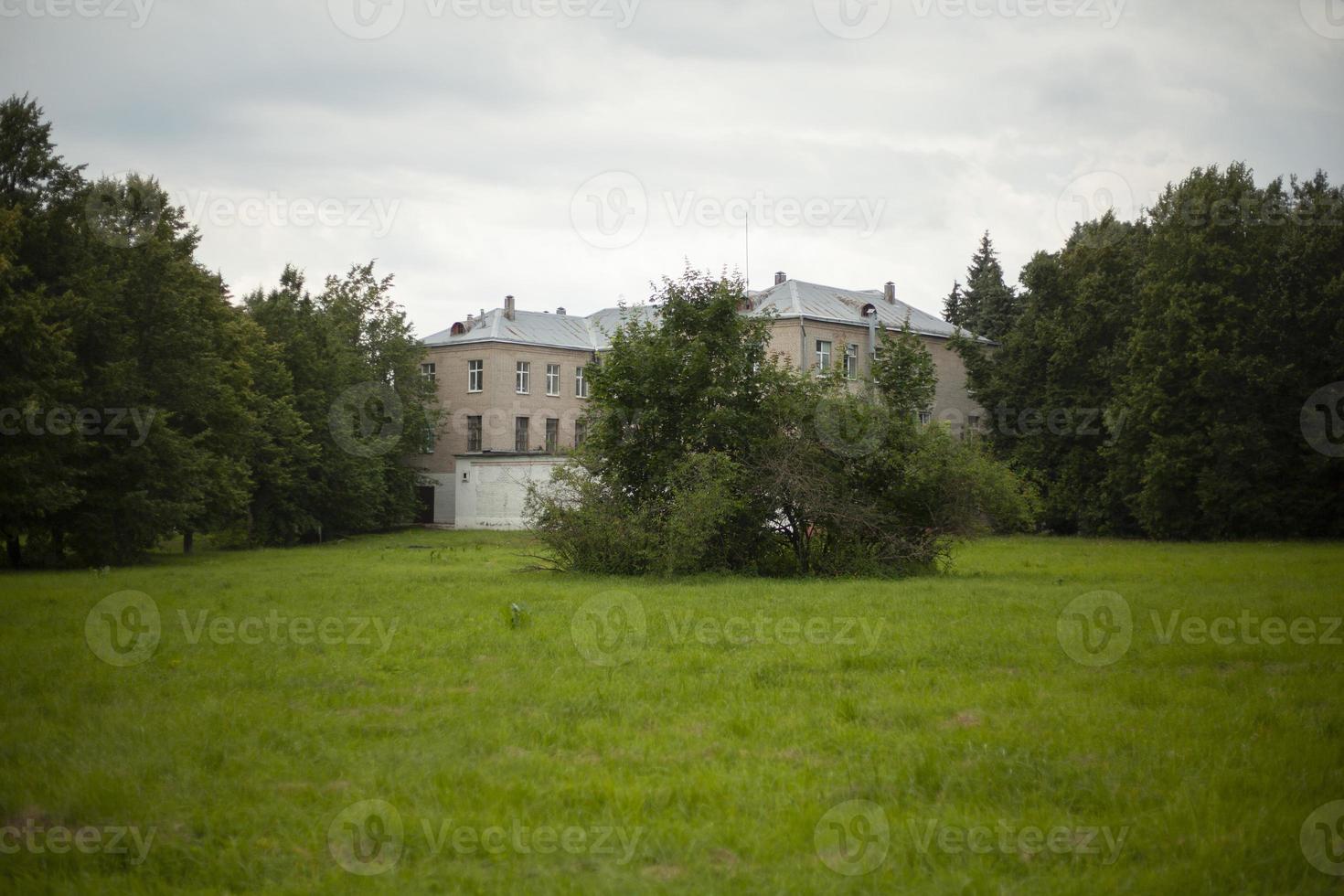 Building in park. Old building among trees. House stands at end of park. Green lawn. photo
