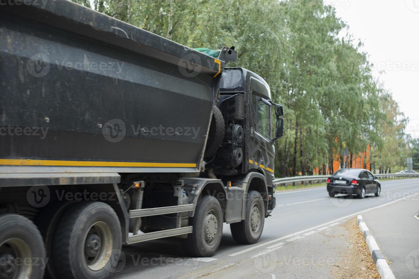 Black truck on road. Freight transport on highway. Car with body. Great trailer. photo