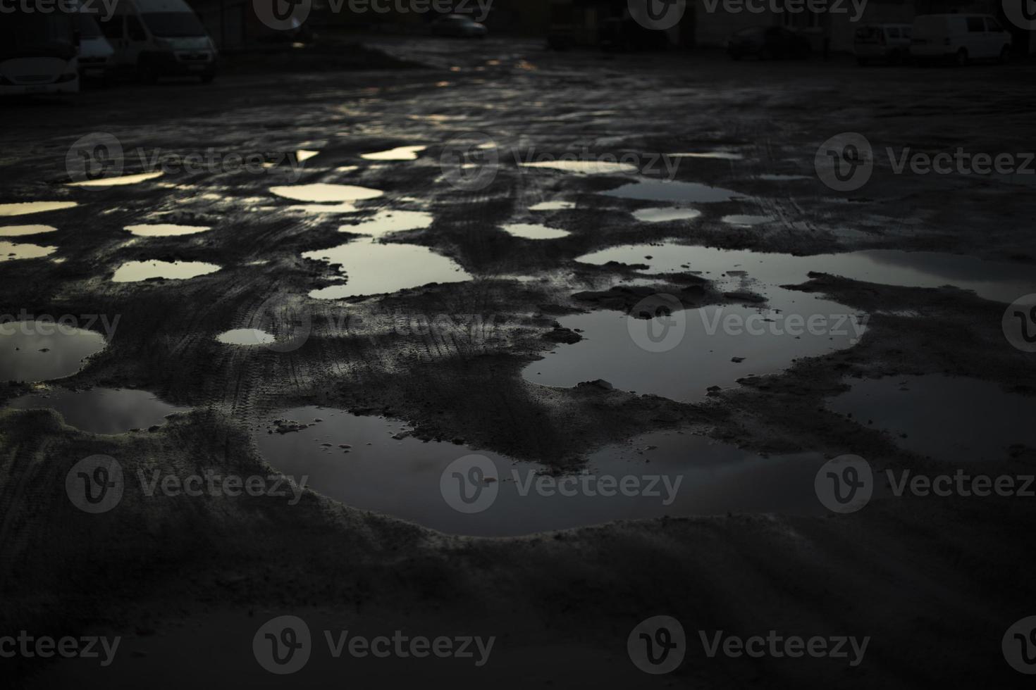 Large puddle in dark. Reflection of light in puddle. Bad road in Russia. photo