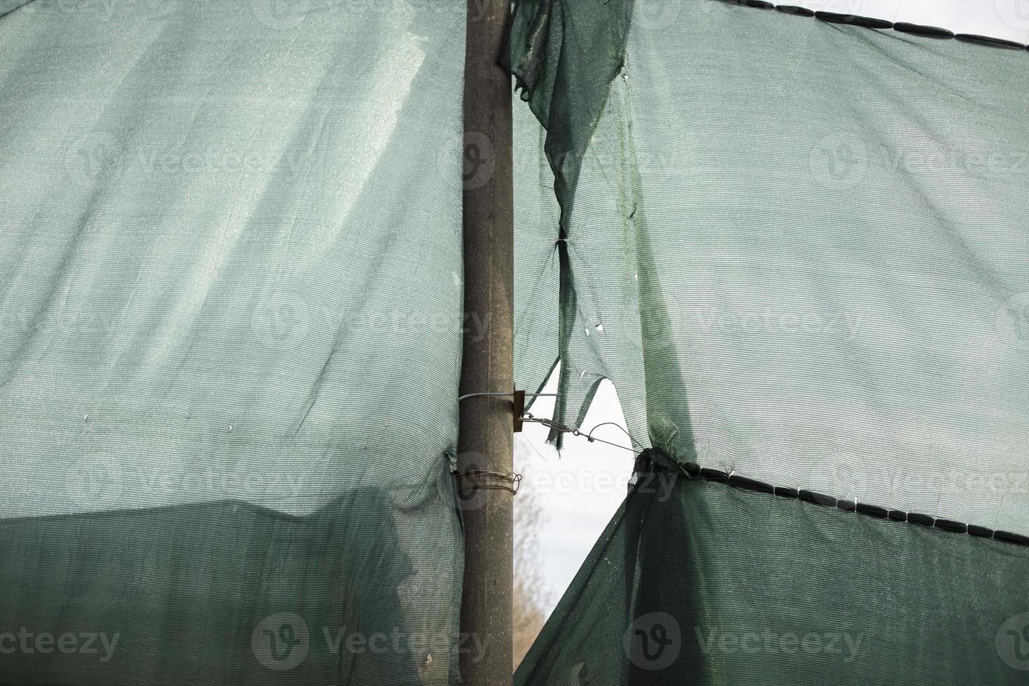 Torn grid in stadium. Green grid around site. Torn fabric. photo