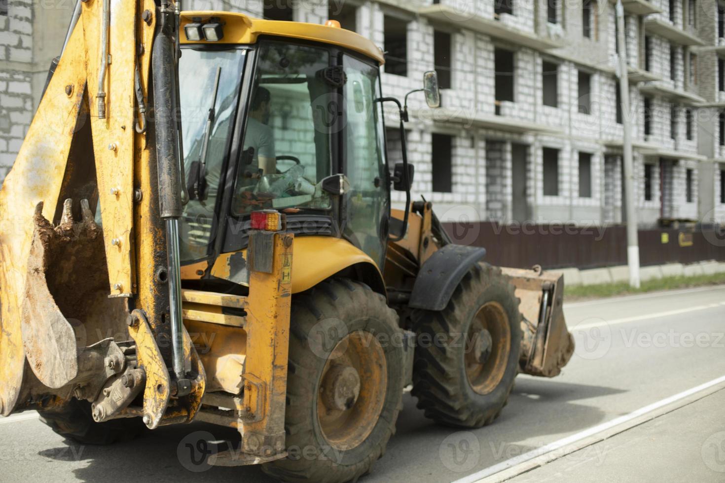 tractor amarillo, maquinaria de construcción en la ciudad. vehículos pesados con ruedas grandes. foto