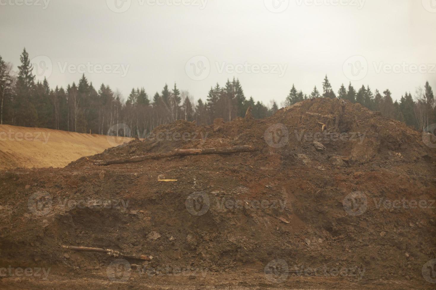 Mountain of sand on line. Excavated earth. Start of construction of road junction. photo