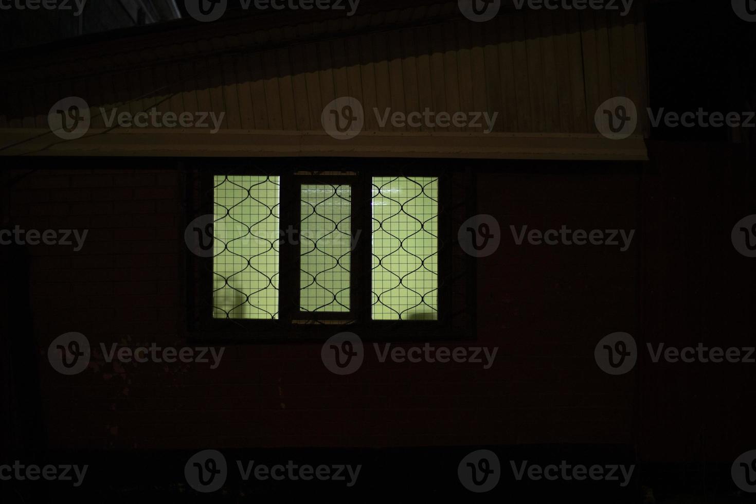 Window is in dark. Grille on window in building. photo