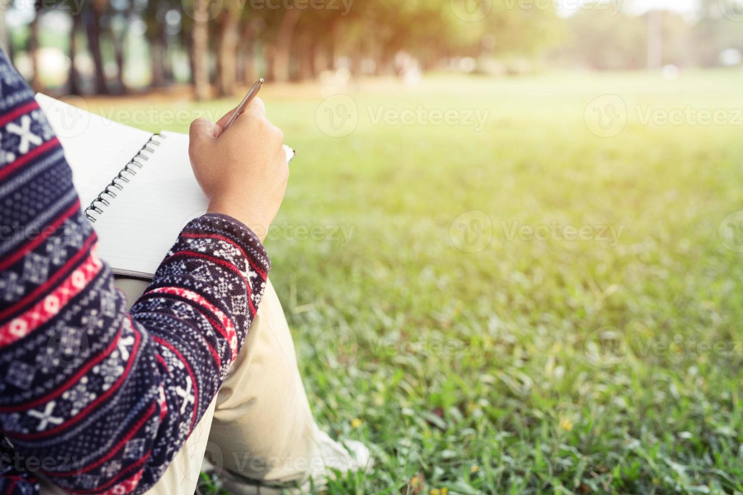close up hand young man are sitting using pen writing Record Lecture notepad into the book. photo