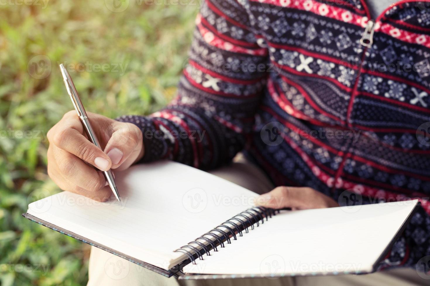 close up hand young man are sitting using pen writing Record Lecture notepad into the book. photo
