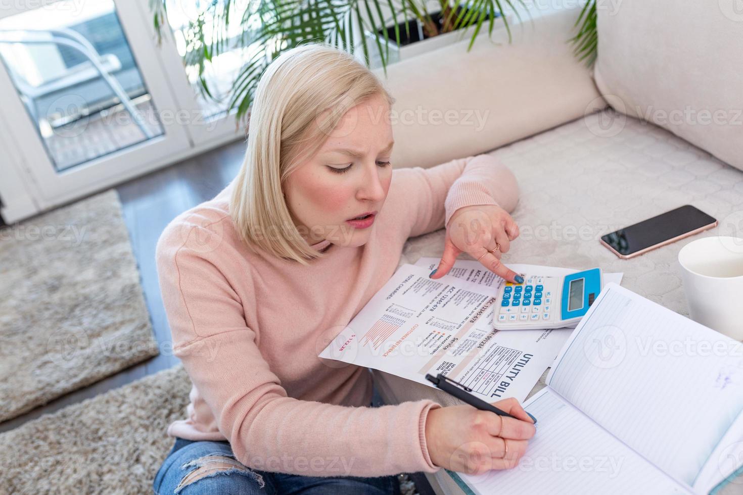 Candid shot of beautiful young Albino woman sitting with calculator and bills, doing paperwork. Hand woman doing finances and calculate on desk about cost at home office.Concept finances and economy photo