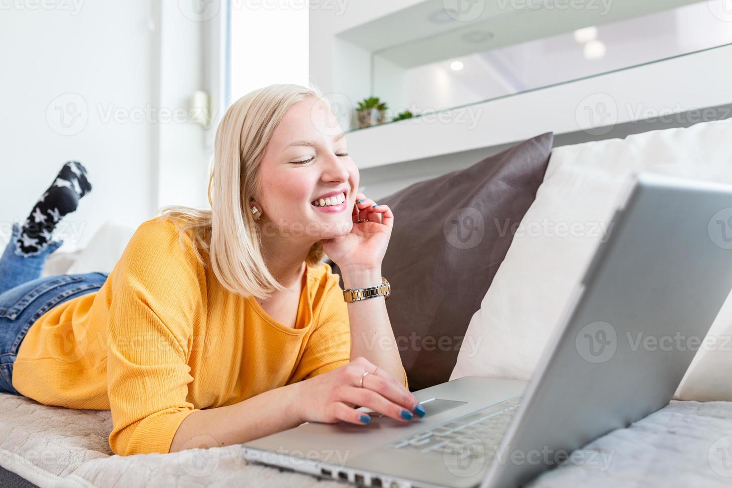 Young albino woman doing research work for her business. Smiling woman sitting on sofa while browsing online shopping website. Happy girl browsing through the internet during free time at home. photo