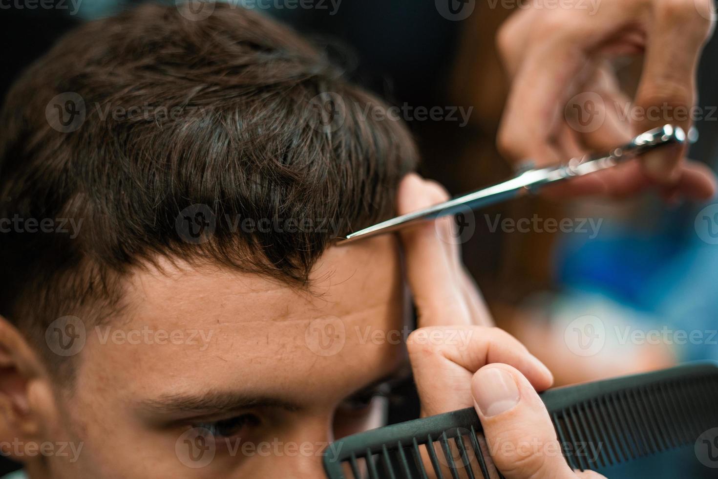 Barbershop. Close-up of man haircut, master does the hair styling in barber shop. Close-up, master Barber does the hairstyle and styling with scissors. Concept Barbershop. photo