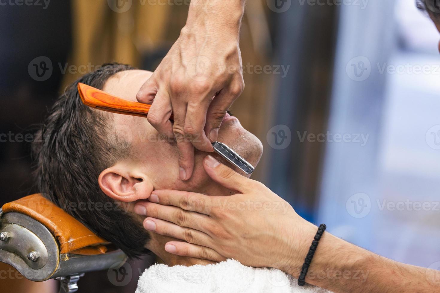 maquinilla de afeitar en manos de peluquero especialista. peluquero  afeitando a un hombre en una peluquería, primer plano. hombre con bigotes  afeitándose 11668397 Foto de stock en Vecteezy