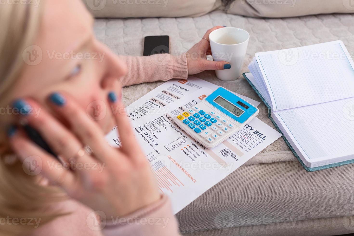 Beautiful young Albino woman sitting with calculator and bills, doing paperwork. Hand woman doing finances and calculate on desk about cost at home office.Concept work from home photo