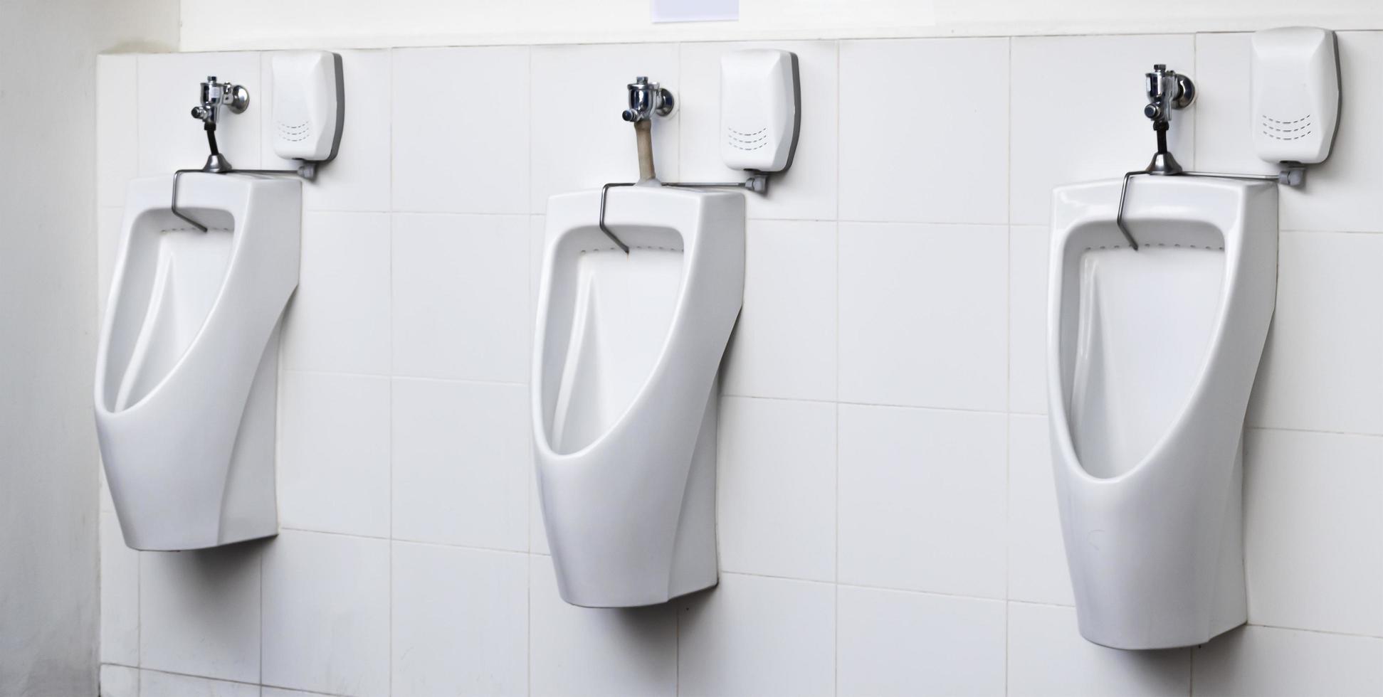 Men's room with white porcelain urinals in line photo