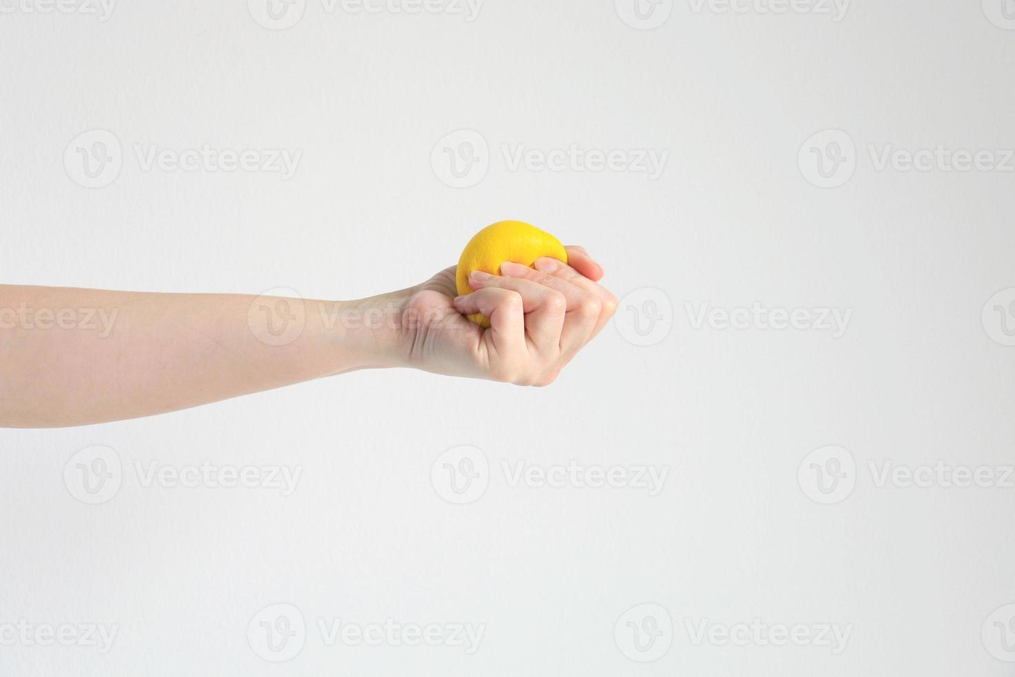 Hand pressing yellow squishy ball for exercise muscle or for feeling relax from stress in concept of health care and medical. photo