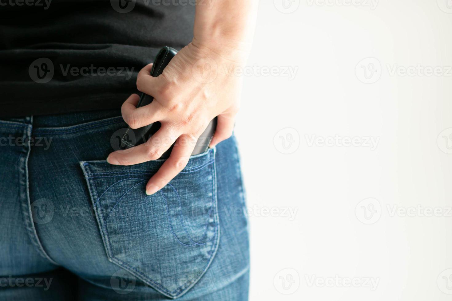 A woman keeps a short wallet in the back pocket of jeans on a white background with copy space. photo