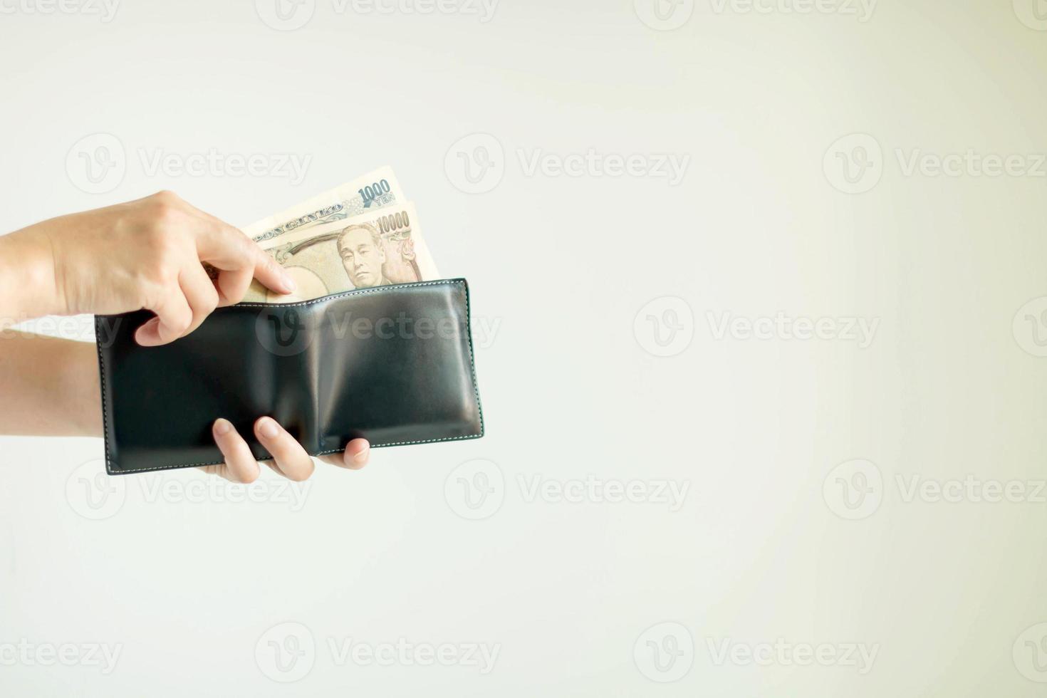 A hand is picking Japan paper money in the currency of Yen or JPY from the short wallet for payment. photo