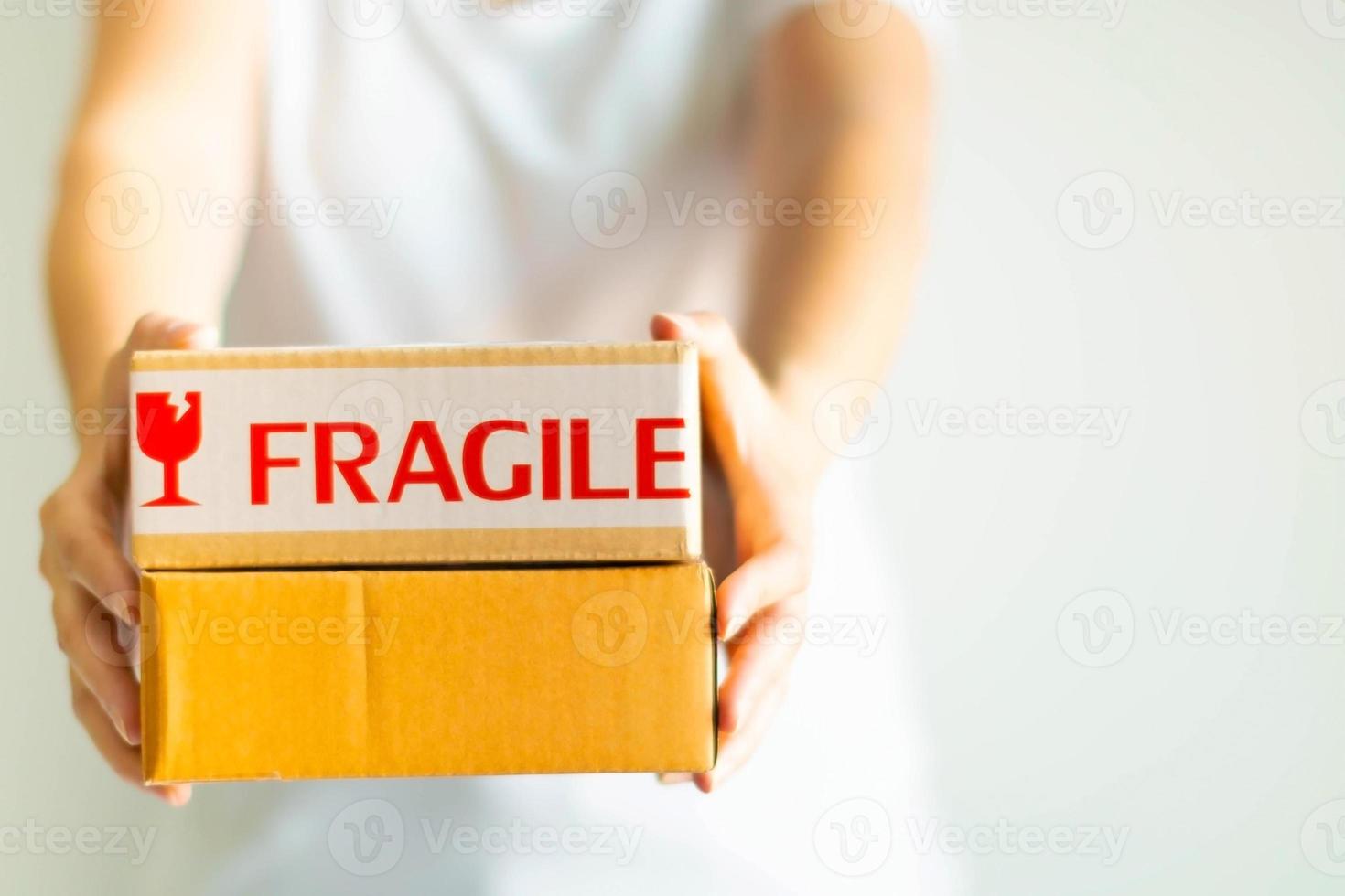 Close-up image of two hands holding and offer two parcel boxes on white background, selective focus. photo