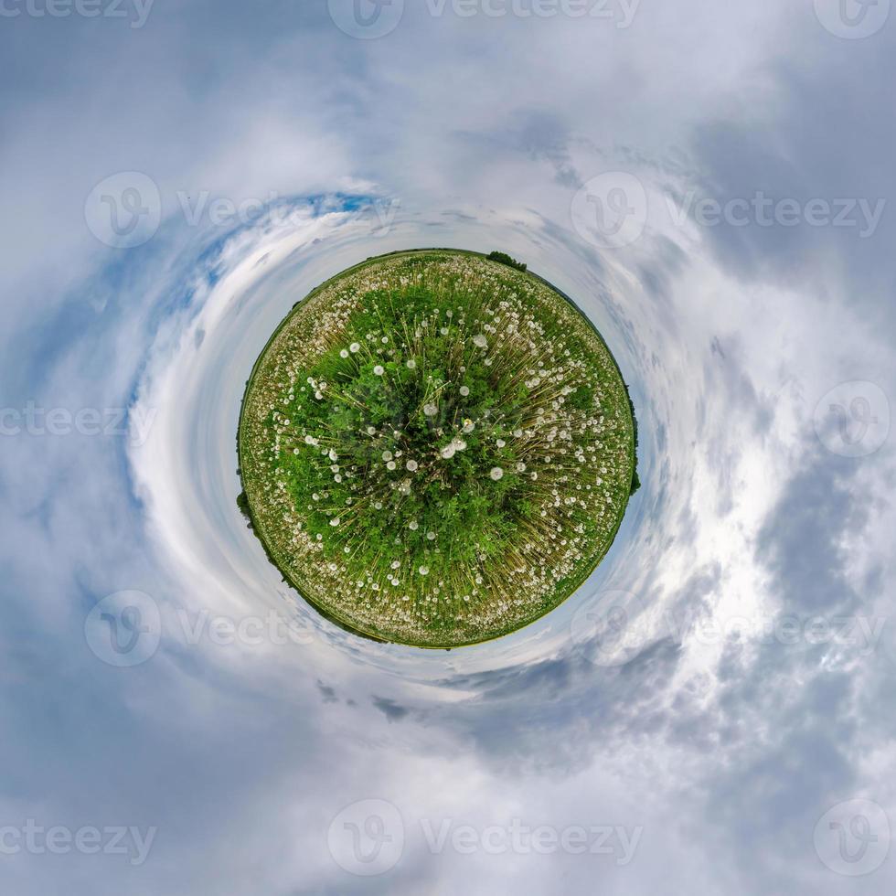 Little planet transformation in dandelions field of spherical panorama 360 degrees in spherical abstract aerial view with awesome beautiful clouds. Curvature of space. photo